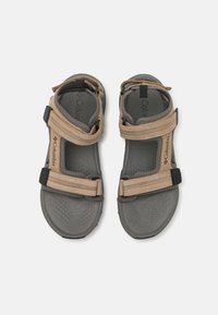 Brune og grå sandaler har justerbare remmer, teksturerte såler og en sikker passform, designet for utendørsbruk. Columbia-merket er inkludert.