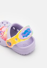 Zuecos de color lavanda para niños con diseño de Peppa Pig y tira ajustable multicolor que presenta ilustraciones de dibujos animados y un detalle en forma de corazón.