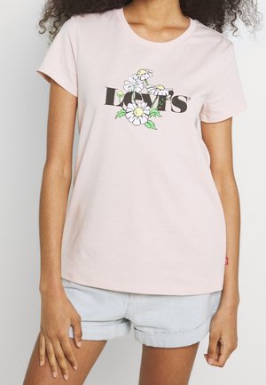 Vaaleanpunainen puuvillainen t-paita pyöreällä kaula-aukolla, jossa musta logo ja etuosassa keskeinen kukkakuvio. Lyhyet hihat, rento istuvuus.