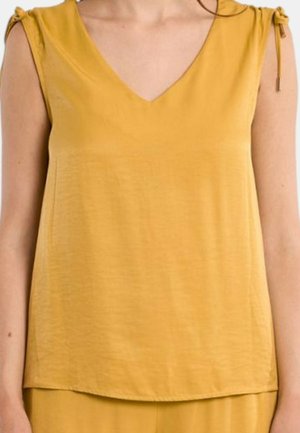 Top senza maniche giallo senape con scollo a V e dettagli legati sulle spalle, indossato da una persona, corto a metà busto.