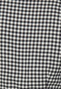 Černobílá kostkovaná tkanina s kostkovaným vzorem. Design obsahuje malé čtverce, které jsou rovnoměrně rozmístěné, s jemnou texturou.