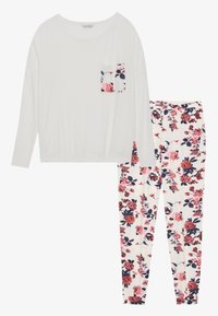 Λευκή μπλούζα με μακριά μανίκια και λουλουδάτη τσέπη, συνδυασμένη με παντελόνια πυζάμας με λουλουδάτο μοτίβο σε κρέμα, κόκκινες και ναυτικές αποχρώσεις. Μαλακό και ελαφρύ ύφασμα.
