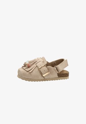 Sandalia para niño pequeño de ante beige con hebilla dorada, detalle de flecos, cuentas de colores y suela de corcho, talón abierto con tira ajustable.