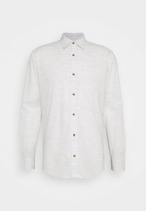 Chemise blanche à manches longues avec col et tissu légèrement texturé, présentée sur fond clair uni.