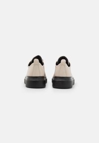 Beige Wildlederschuhe mit einer schwarzen Gummisohle. Abgerundete Zehenpartie, Rückenschlaufe und eine glatte Textur. Minimalistisches Design, geeignet für die Freizeit.