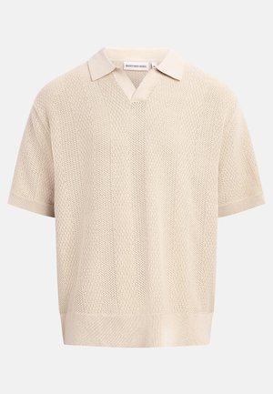 Polo a maniche corte lavorata a maglia color beige con collo aperto e motivo verticale a rilievo.