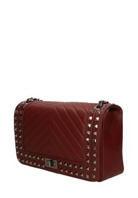 Borsa in pelle rossa con trapuntatura a zig zag, dettagli in metallo argentato lungo i lati e chiusura rettangolare in metallo.