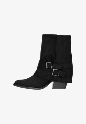 Schwarzer Wildleder-Stiefelette mit zwei dekorativen Riemen und silbernen Schnallen, niedriger Blockabsatz, spitze Zehen, Seitenansicht auf weißem Hintergrund.