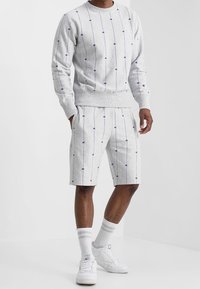Grijze sweatshirt- en shortset met verticale lijnen en paarse accenten. Gemaakt van zachte stof met geribbelde manchetten en tailleband.