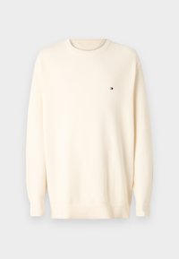 Maglione a maglia color crema con maniche lunghe, collo rotondo e polsini a coste. Presenta un piccolo logo sul petto. Tessuto testurizzato.