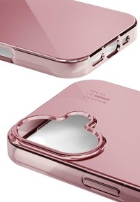 Coque de téléphone rose avec une finition brillante, présentant une découpe en forme de cœur et un logo gravé. Les ports d'accès sont clairement visibles.