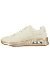 Jasno beżowe sneakersy z gładką syntetyczną cholewką, perforowanymi akcentami, złotymi detalami oraz widoczną poduszką powietrzną w podeszwie. Gumowa podeszwa.