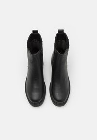 Sorte lær ankelsko med en glat tekstur, elastiske sidepaneler og en løkke til nem påtagning. Minimalistisk design med en afrundet tå.