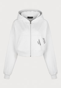 Sudadera corta blanca hecha de una tela suave, con una cremallera frontal, dos bolsillos y texto impreso en la manga izquierda.