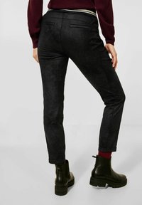Svarta mocka-look skinny byxor med slim fit, medelhög midja och två bakfickor. Matchas med svarta ankelboots och burgundy-strumpor.