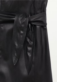 Vêtement en cuir noir avec une taille ceinturée. Texture lisse avec des coutures détaillées le long des coutures et de la ceinture pour un design amélioré.