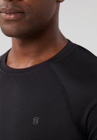 Black athletic shirt with a crew neckline, smooth texture, and subtle stitching details. Features a small logo on the chest.