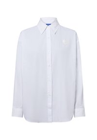 Weißes Langarmhemd mit Knopfleiste und spitzem Kragen sowie einem kleinen herzförmigen gestickten Patch auf der linken Brust.