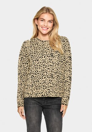 Beiger Pullover mit Leopardenmuster und schwarzen Flecken. Lange Ärmel, runder Halsausschnitt und geripptem Saum. Weicher Stoff, lässiges Design, kombiniert mit dunklen Jeans.