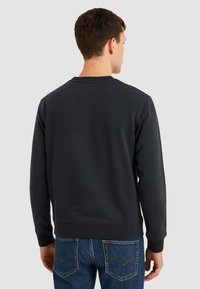 Felpa girocollo grigio scuro con colletto e polsini a costine, texture morbida e vestibilità classica, abbinata a jeans di denim blu.