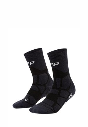 Schwarze Sportsocken mit verstärkter Polsterung und weißem Logo-Schriftzug am Bündchen und an der Sohle, konzipiert für den rechten und linken Fuß.