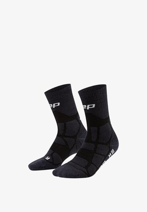 Schwarze Sportsocken mit verstärkter Polsterung und weißem Logo-Schriftzug am Bündchen und an der Sohle, konzipiert für den rechten und linken Fuß.