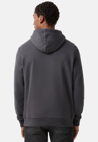 Grijze hoodie met een zachte textuur, met een capuchon en geribbelde manchetten. Het ontwerp heeft een relaxte pasvorm en wordt gedragen over donkere spijkerbroeken.