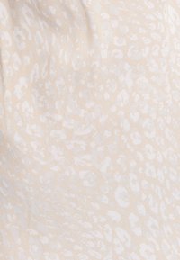 Tissu beige clair présentant un motif animalier blanc subtil, avec une texture douce et une apparence légère.