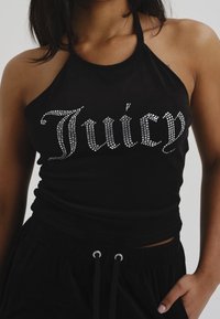 Svart haltertopp i slät tyg med en "Juicy"-logotyp i silverfärgade strassstenar över framsidan. Bärs med svarta byxor med dragsko.
