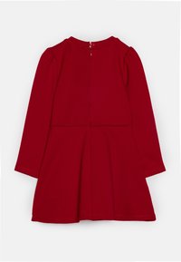 Rotes Langarmkleid mit tailliertem Oberteil, ausgestelltem Rock, Rundhalsausschnitt und Reißverschluss hinten. Hergestellt aus weichem, glattem Stoff ohne Muster.