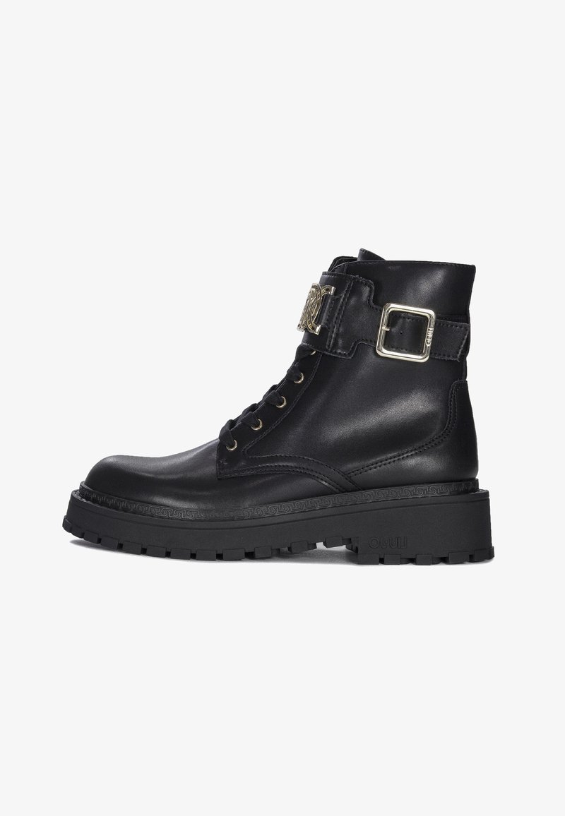 Black leather combat boot with thick lug sole, front laces, ankle strap, and decorative gold buckle on a white background.