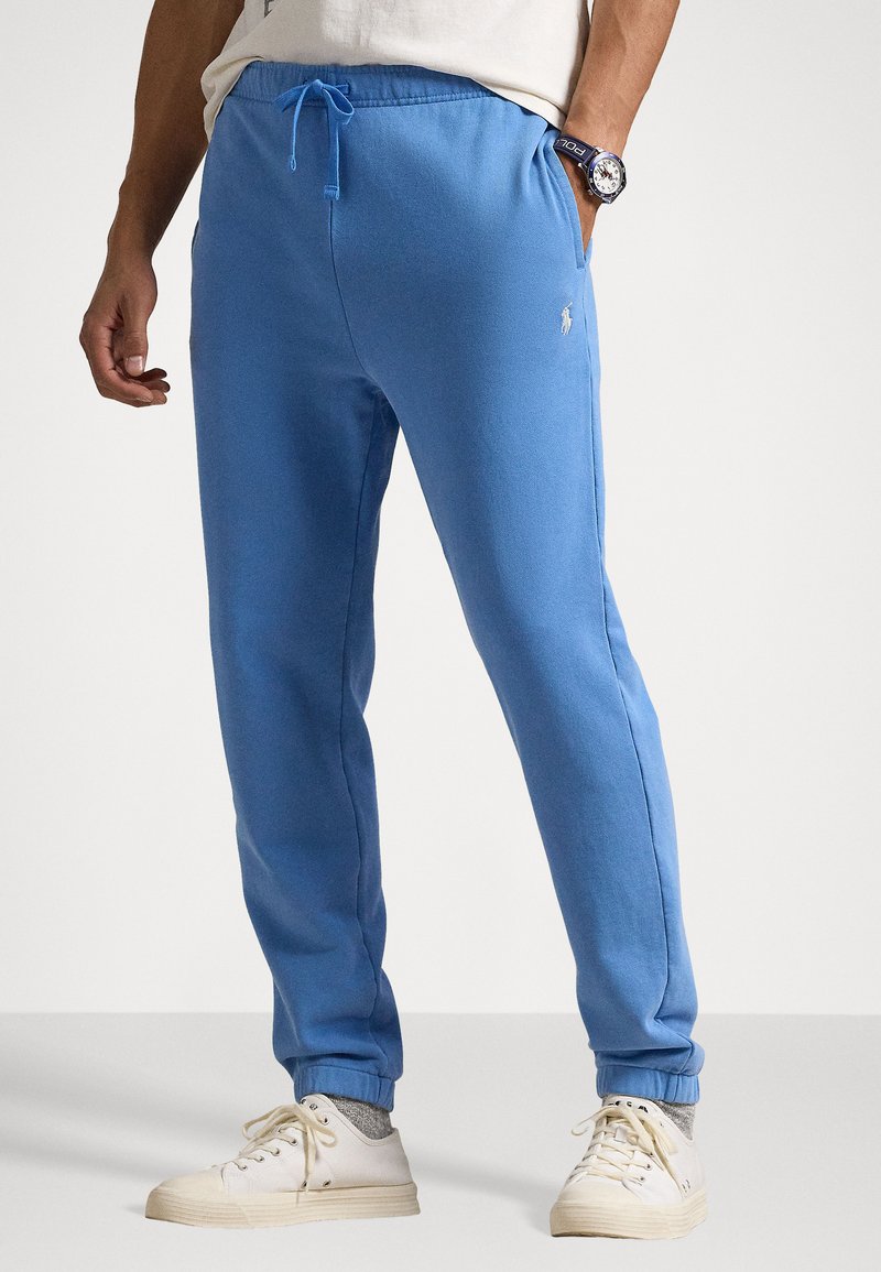 Pantaloni de jogger de un albastru deschis, realizați dintr-un material moale, având talie elastică cu șnur, buzunare laterale și mansete ribbate la gleznă.