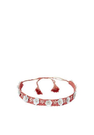 Diadema de tela tejida roja con adornos de flores blancas y borlas. Presenta una banda delgada y texturizada y lazos ajustables.