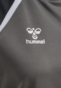 Grauer Sportstoff mit weißen und schwarzen Akzenten, der ein weißes stilisiertes Bienenlogo und den Markennamen "hummel" zeigt.