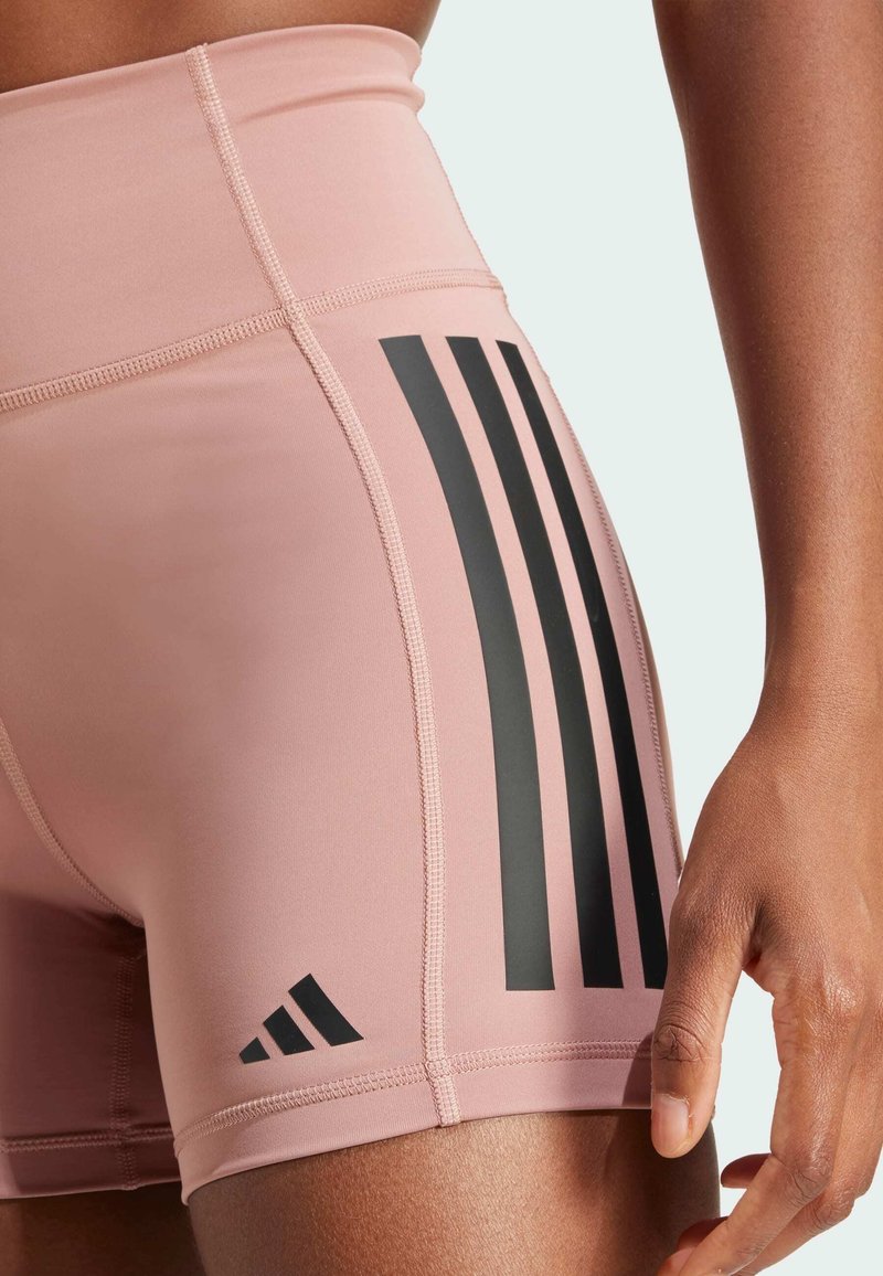 Shorts de sport roses avec une taille haute, des rayures noires en accent et des détails de couture. Fabriqués en tissu extensible et lisse.