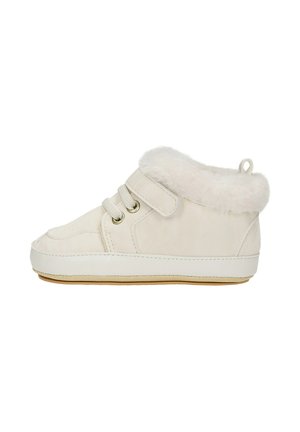 Zapato de bebé beige claro con forro de piel suave, cierre de cordones y cinta de velcro, y suela de goma, vista lateral sobre fondo blanco.