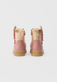 Ζευγάρι ροζ και μπεζ χειμερινών μποτών για παιδιά με επένδυση από γούνα και καφέ καουτσούκ, εμφανιζόμενο από το πίσω μέρος σε λευκό φόντο.