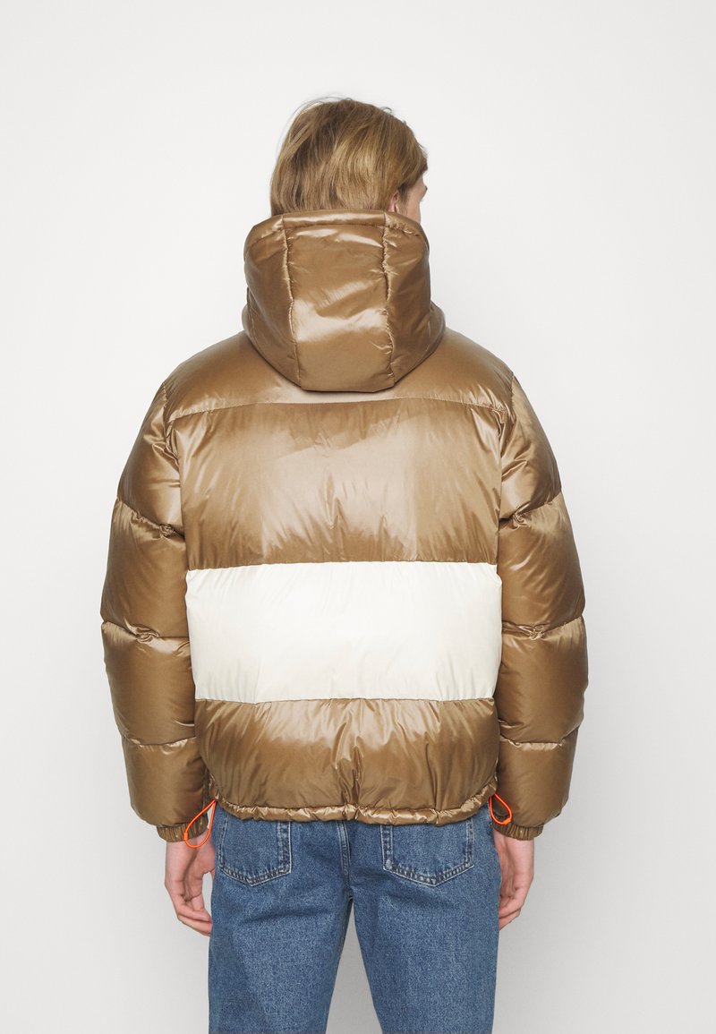 Braune Puffermantel mit Kapuze, ausgestattet mit einem kontrastierenden cremefarbenen horizontalen Streifen. Enthält elastische Bündchen und Kordeln am Saum.