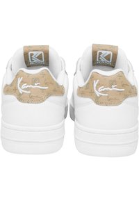 Fehér sneakers bézs mintás sarokpánttal és logó részlettel, sima anyaggal és alacsony profilú dizájnnal.