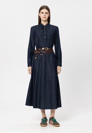 Denim maxi dress with long sleeves, ruffle trim, button placket, and a brown belt. Accented with green and pink laced sneakers.