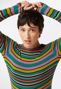 Maglione a maniche lunghe a righe multicolori con audaci motivi in verde, rosa, viola, rosso e nero, con un design aderente e una texture a coste.