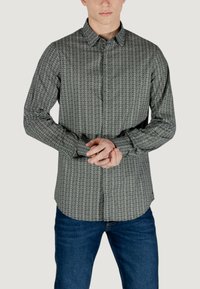 Camicia button-up con motivo bianco e nero, maniche lunghe, colletto, con vestibilità sartoriale e orlo arrotondato, abbinata a jeans blu.