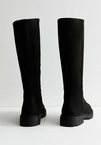 Czarne kozaki do kolan o gładkiej teksturze i bocznym zamku błyskawicznym. Podeszwa jest masywna z teksturowanym uchwytem. Brak widocznych elementów dekoracyjnych.