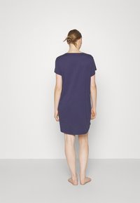 Sukienka z krótkim rękawem, luźno dopasowana, wykonana z granatowej tkaniny, z okrągłym dekoltem i lekko zaokrąglonym dołem sięgającym do połowy uda.