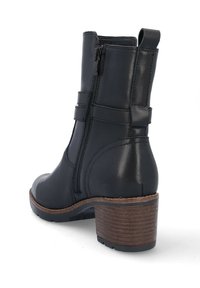 Botín negro de cuero hasta el tobillo con tacón de madera apilado, cremallera lateral, tirador y correa decorativa alrededor del tobillo.