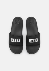 Fekete csúszó szandálok, texturált matt felülettel, széles "REEF" felirattal, fehér színben. Könnyű kialakítású, alkalmi viselethez készült.