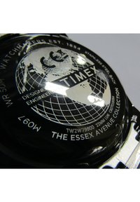 Montre Timex avec un boîtier en acier inoxydable noir, des gravures argentées, un motif de globe et une résistance à l'eau allant jusqu'à 50 mètres. Caractéristiques de la "Collection Essex Avenue."