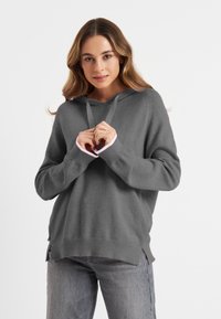 Grauer Kapuzenpullover mit pinken Akzentbündchen, aus weichem Material gefertigt. Er bietet eine lockere Passform und eine Kordel am Hals für Anpassungsmöglichkeiten.
