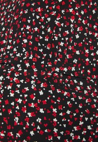 Tissu noir avec un motif floral en rouge et blanc, présentant de petites fleurs dispersées. Texture lisse avec un léger éclat.