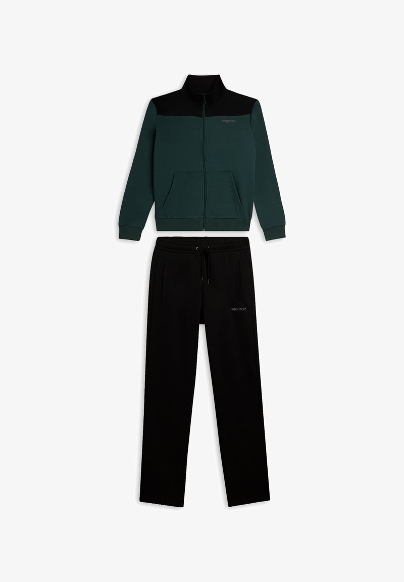 Chaqueta verde oscuro con cremallera y detalles negros, con bolsillos, combinada con pantalones negros con cordón. Ambos están confeccionados con una tela suave y cómoda.